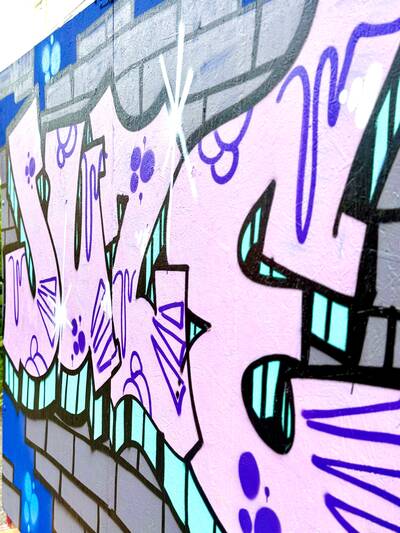 Zu sehen ist ein Gaffiti-Schriftzug "Juze" in rosa und türkis was für Jugendzentrum steht.