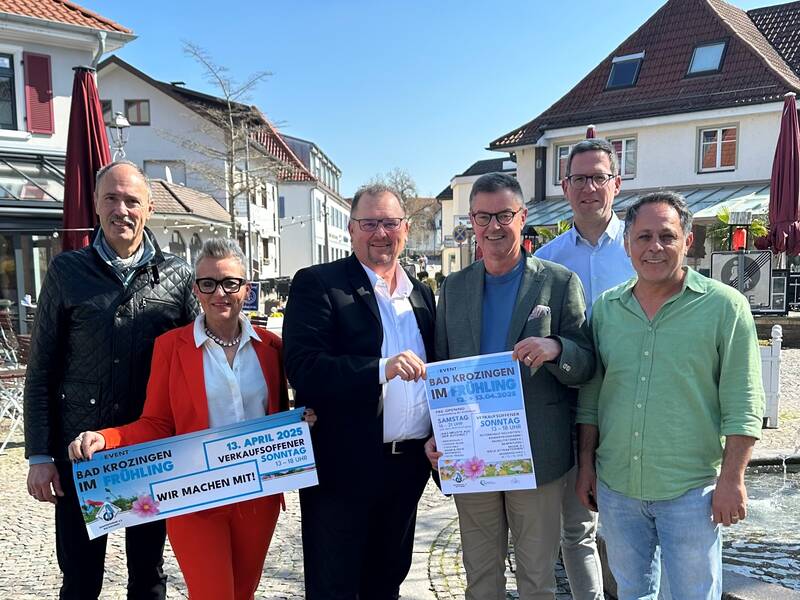Eine Gruppe von sechs Personen (Vorstand Gewerbepark) posiert draußen für ein Foto und hält Schilder mit der Aufschrift "Bad Krozingen im Frühling", die auf eine Veranstaltung am 13. April 2025 hinweisen.
