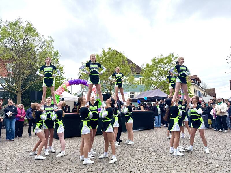 Eine Gruppe von Cheerleadern tritt auf einem öffentlichen Platz (Lammplatz, Bad Krozingen im Frühling) auf, während Zuschauer im Hintergrund zuschauen.