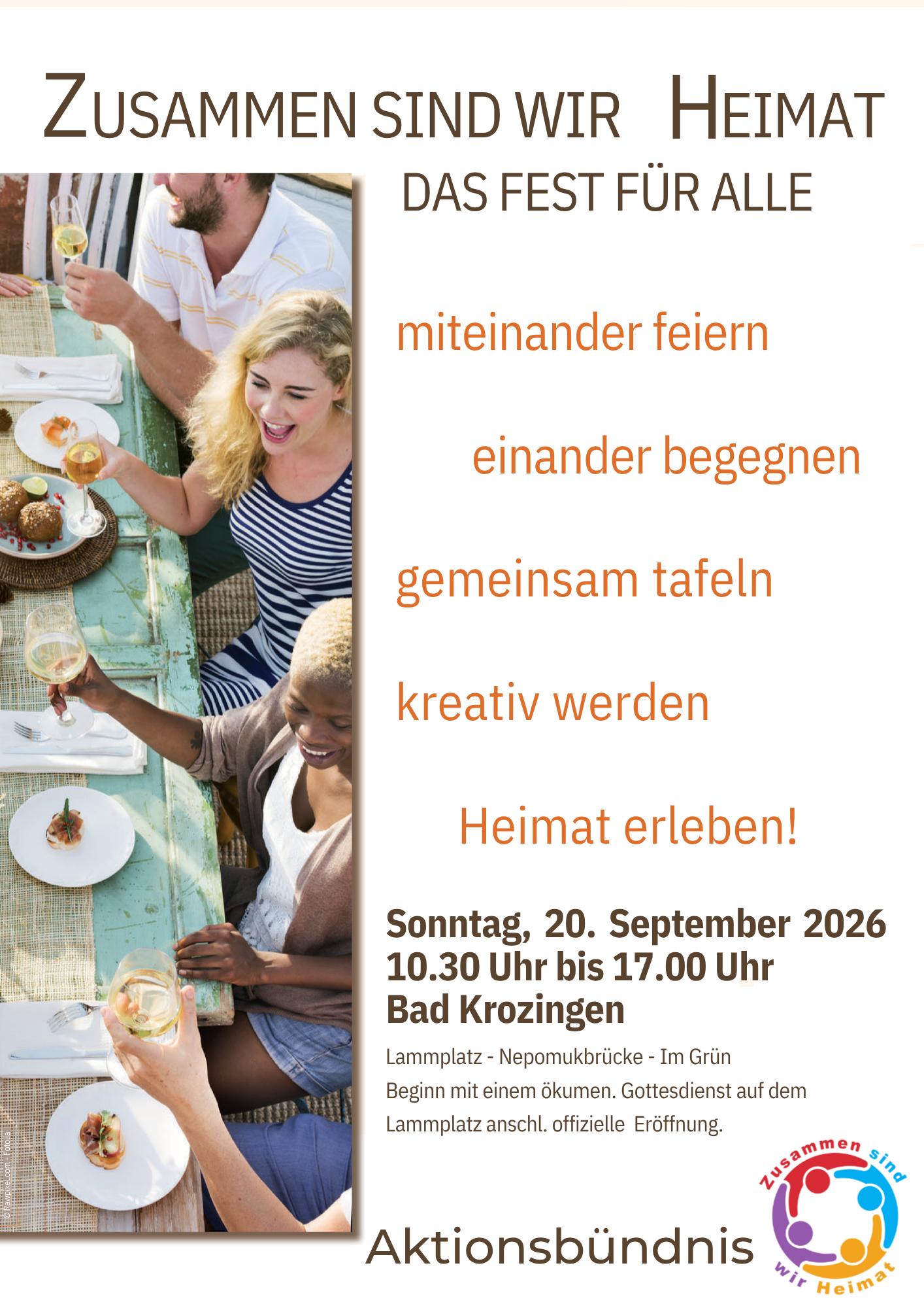 Eine Gruppe von Menschen sitzt lachend an einem gedeckten Tisch bei einem Fest mit dem Motto "Zusammen sind wir Heimat".